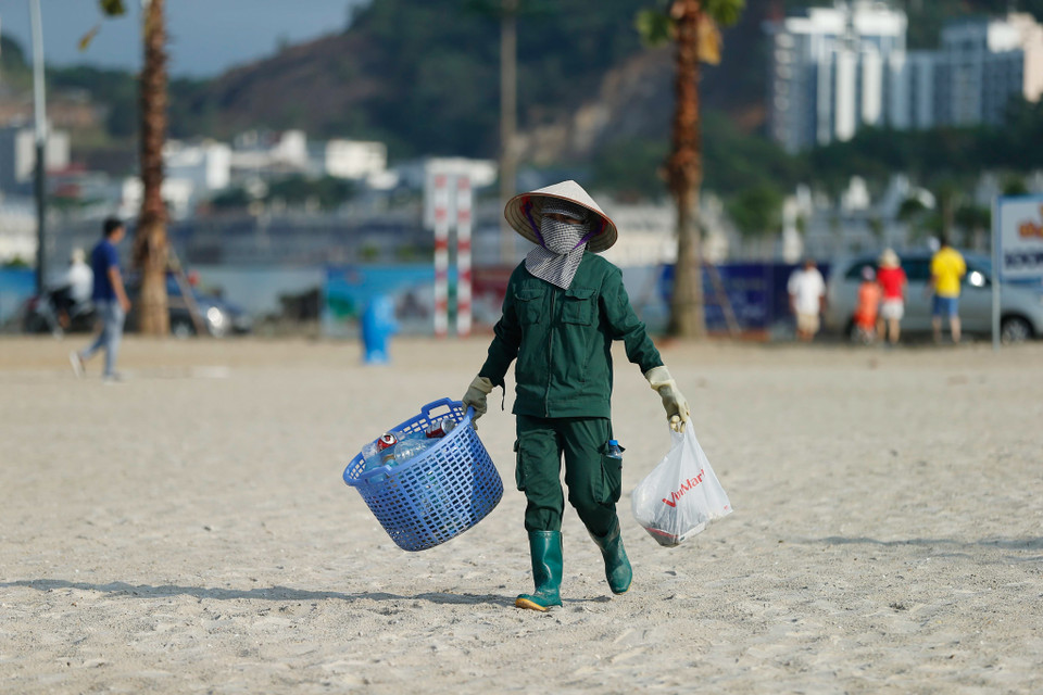 Bất kể nắng hay mưa đội lao công dọn rác vẫn âm thầm làm công việc của mình để mang lại một bãi biển sạch đẹp trong mặt khách du lịch. (Ảnh: Vietnam+)