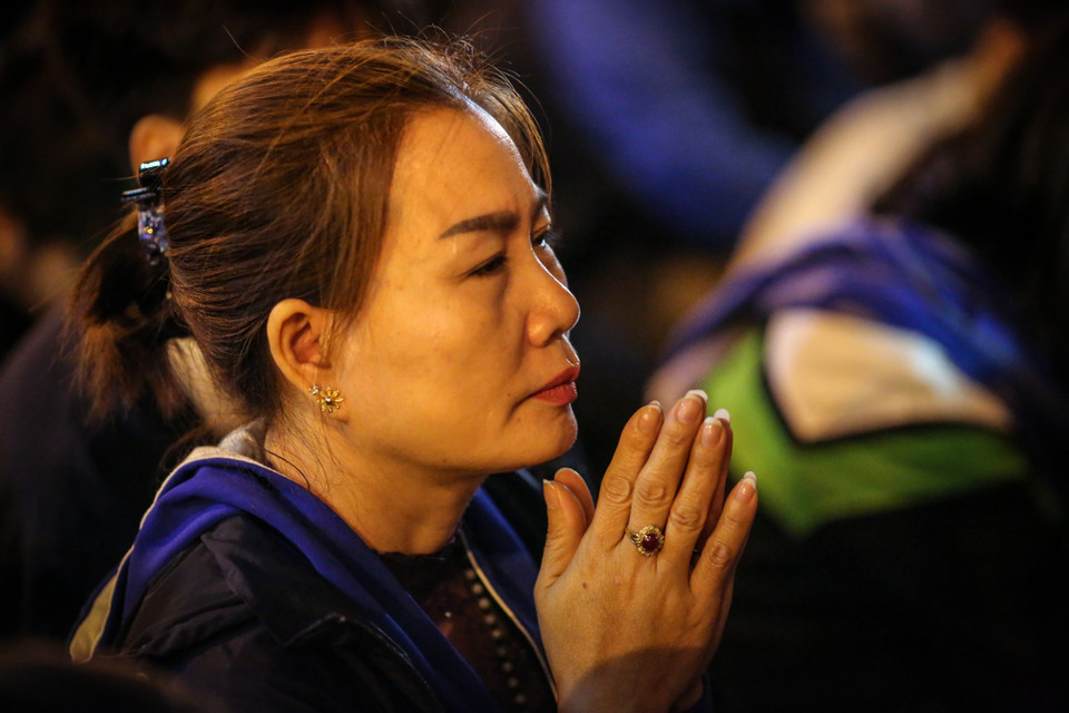 Người dân đứng tràn ra phía đường Tây Sơn, thành tâm chắp tay cầu khấn. (Ảnh: Minh Sơn/Vietnam+)