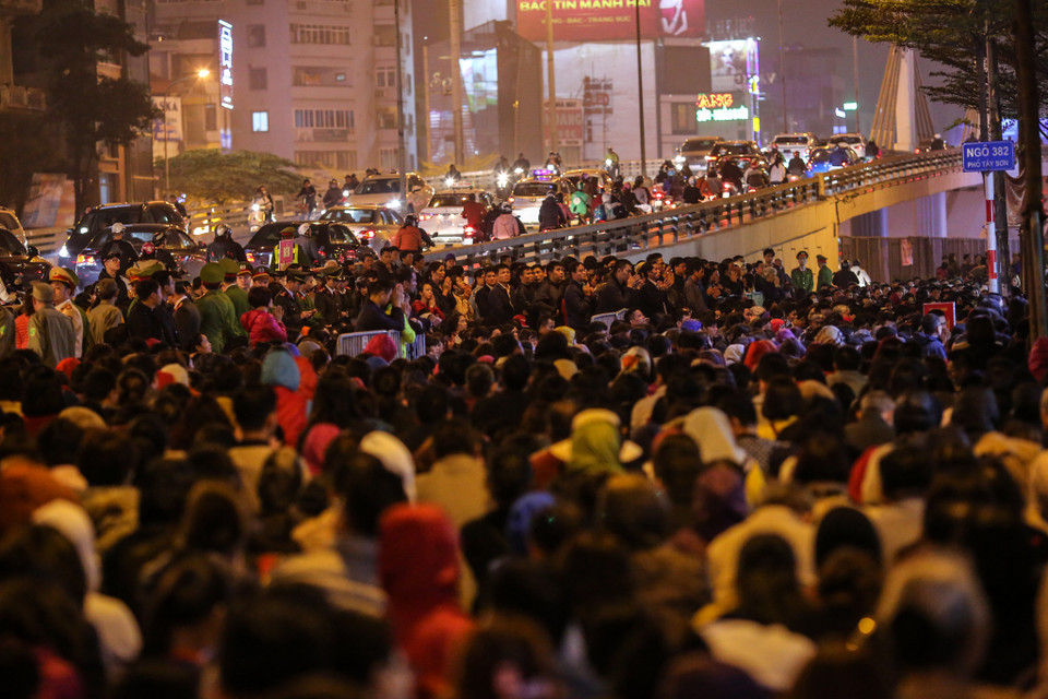 Không thể chen chân vào khu vực làm lễ, nhiều người đành đứng ngoài đường, hoặc trên cầu vượt Ngã Tư Sở để vái vọng vào. (Ảnh: Minh Sơn/Vietnam+)