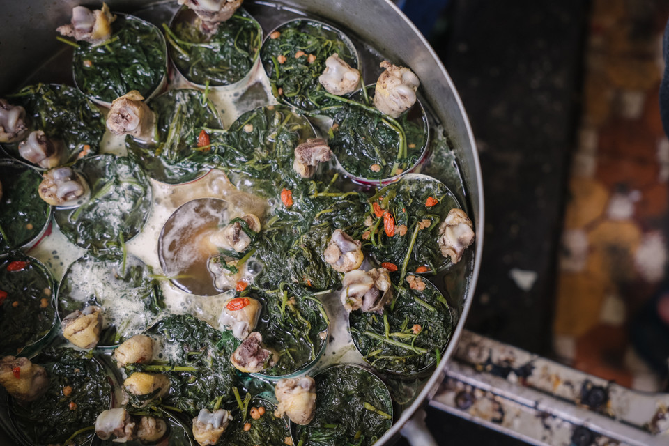 Mì được chần qua nước hầm gà cho ngọt sau đó bỏ vào bát, lúc này những chiếc đùi gà đựng trong lon sẽ được lấy ra, chan nước dùng nghi ngút khói. (Ảnh: Minh Sơn/Vietnam+)