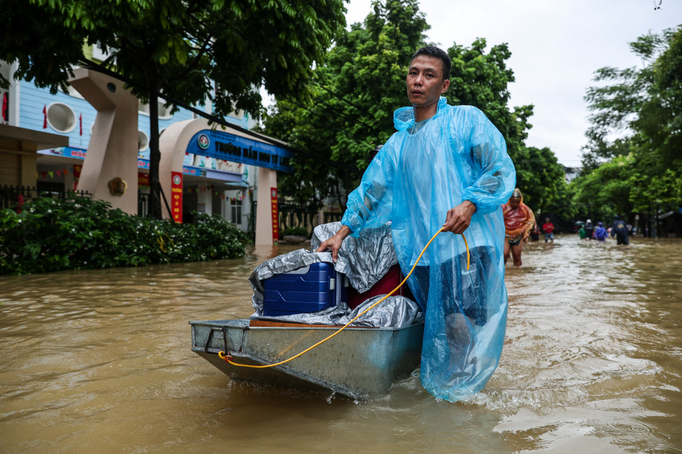 Có những hộ gia đình phải mượn thuyền để vận chuyển đồ đạc, bọc xe máy lại bằng bạt để tránh hư hại. (Ảnh: Minh Sơn/Vietnam+)