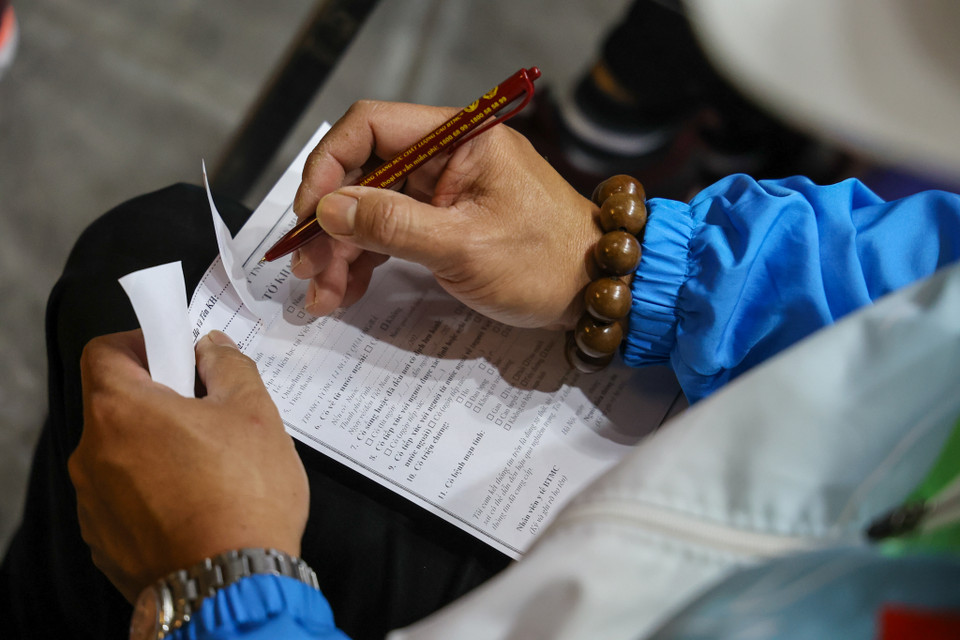 Các khách hàng trước khi giao dịch phải viết vào tờ khai y tế để đảm bảo công tác phòng dịch bệnh. (Ảnh: Minh Sơn/Vietnam+) 