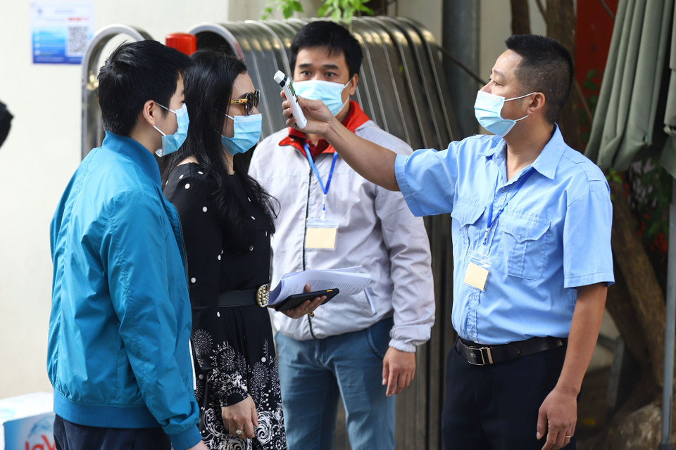 Đến điểm tiêm, các học sinh cũng như phụ huynh được đo nhiệt đô, sát khuẩn tay đồng thời quét mã QR. (Ảnh: Hoài Nam/Vietnam+)