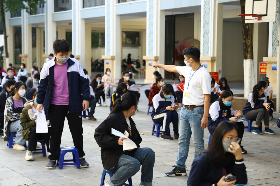 Giáo viên phối hợp với phụ huynh hướng dẫn các học sinh ngồi đảm bảo giãn cách trước khi tiêm. (Ảnh: Hoài Nam/Vietnam+)