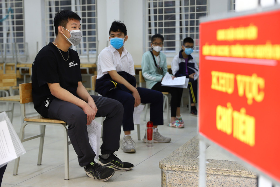 Học sinh ngồi đảm bảo giãn cách trong phòng chờ trước khi tiêm. (Ảnh: Hoài Nam/Vietnam+)