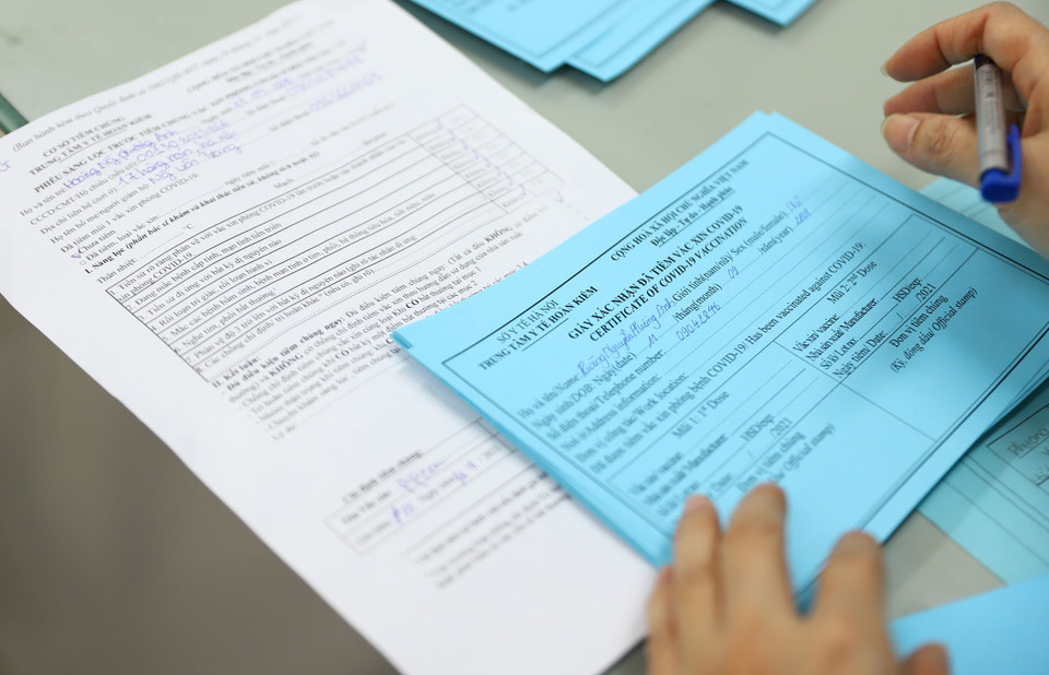 Giáo viên nhà trường sẽ tiến hành ghi thông tin vào giấy xác nhận tiêm chủng cho các em học sinh. (Ảnh: Hoài Nam/Vietnam+)