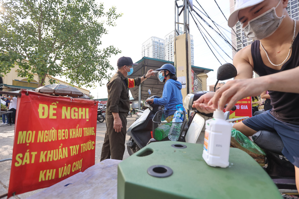 Uỷ ban Nhân dân phường đã cho lắp hàng rào, phân luồng người ra vào và tổ chức cắt cử lực lượng đo thân nhiệt đồng thời kiểm soát phiếu người ra vào chợ nhanh chóng và đảm bảo khoảng cách. (Ảnh: Minh Sơn/Vietnam+)