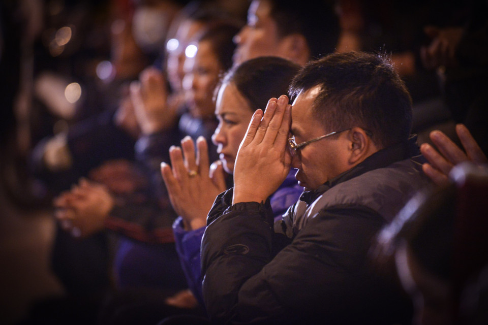 Ở phía ngoài, mọi người chắp tay hướng về phía chùa Phúc Khánh, nơi các nhà sư đang làm lễ cầu an, giải hạn. (Ảnh: Minh Sơn/Vietnam+)