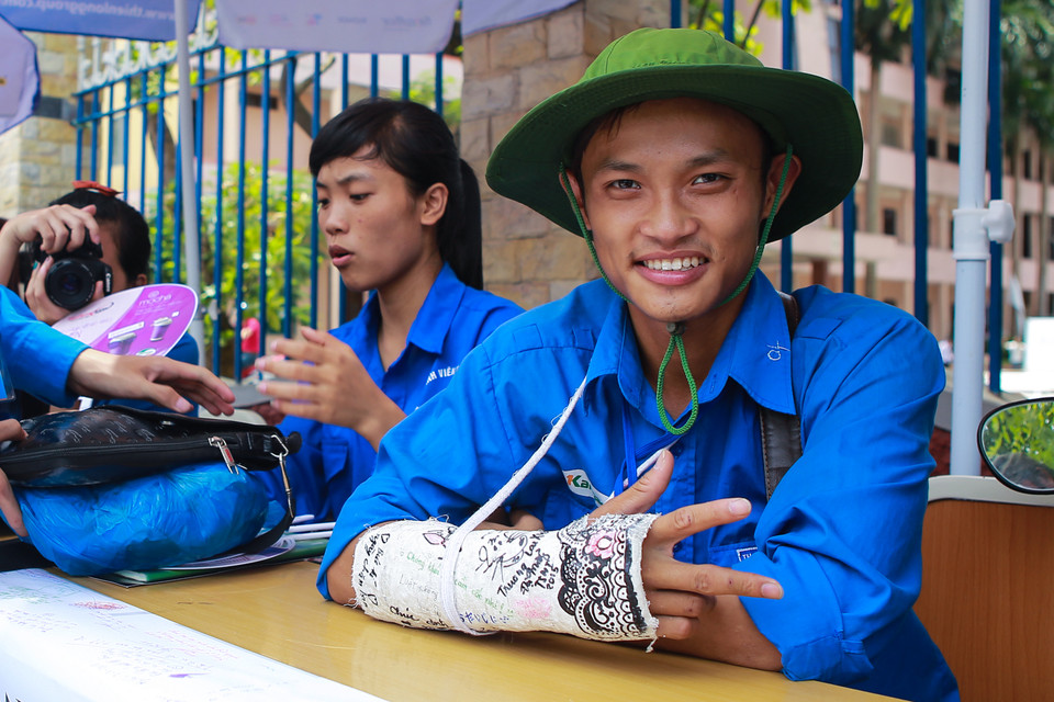 Một bạn nam dù bị gãy tay vẫn cố gắng tham gia công tác tình nguyện. (Ảnh: Minh Sơn/Vietnam+)