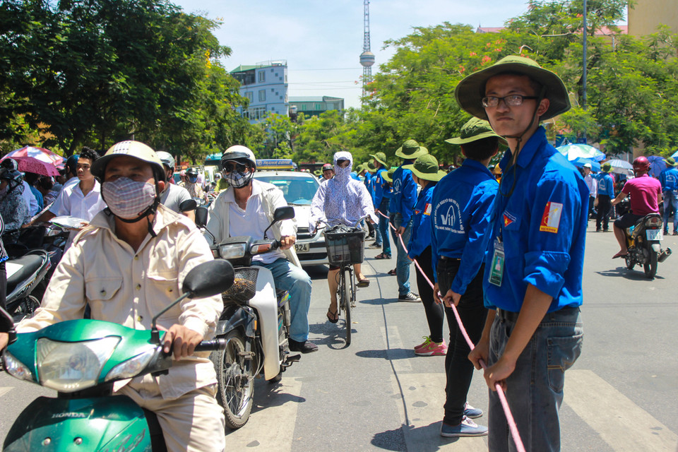 Căng mình giữa trời nắng nóng để làm ‘dải phân cách sống’ để điều tiết giao thông. (Ảnh: Minh Sơn/Vietnam+)