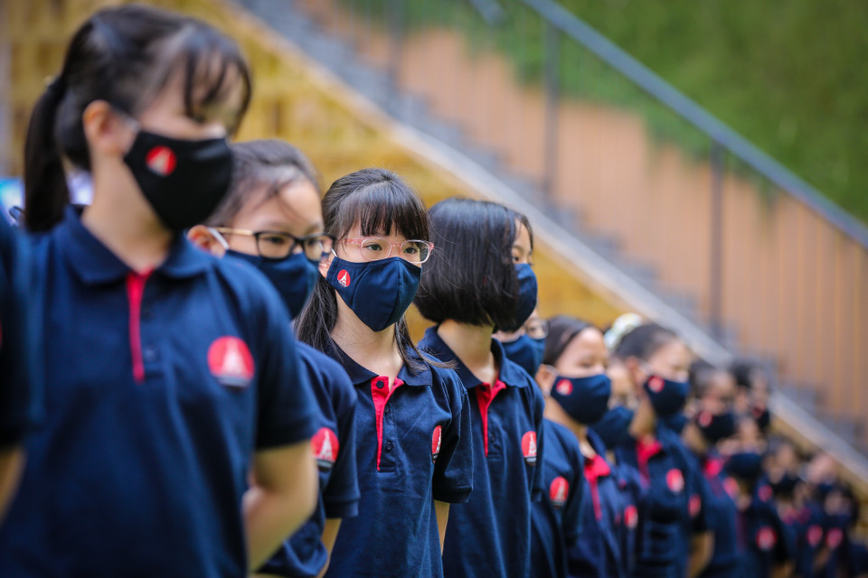 Các em học sinh lớp 6 đều bắt buộc phải đeo khẩu trang để tham dự lễ khai giảng trực tiếp dưới sân trường. (Ảnh: Minh Sơn/Vietnam+) 