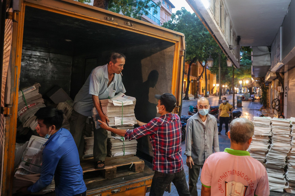 Hằng ngày, cứ vào khoảng 4 giờ 30, trên vỉa hè con phố Đinh Lễ (Quận Hoàn Kiếm) lại rộn ràng cảnh hàng chục người phân loại, giao báo. (Ảnh: Minh Sơn/Vietnam+)