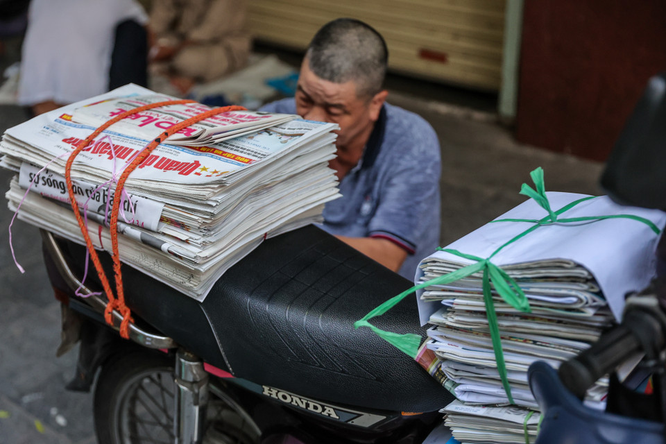 Những người phân loại báo tại đây cho biết hầu hết chủ sạp báo đều gặp khó khăn khi người dân chuyển qua đọc báo mạng. 'Trước đây, tôi giao 4-5 ngàn tờ báo mỗi ngày, bây giờ chỉ còn 1 ngàn tờ. Lượng người ngồi đây phân phối báo cũng đã giảm đi một nửa.' (Ảnh: Minh Sơn/Vietnam+)