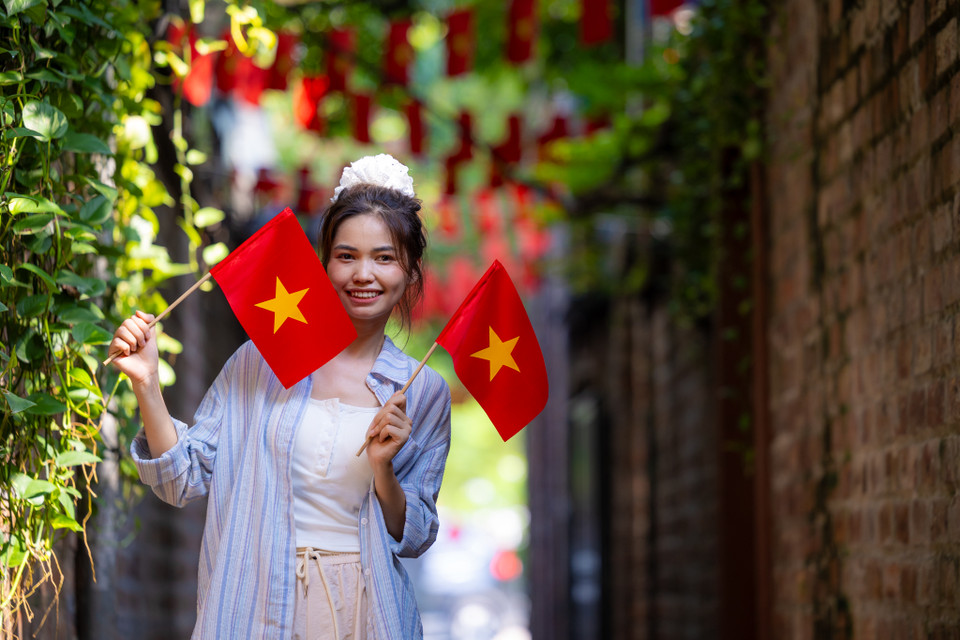 Ngay từ sáng sớm, Nguyễn Thị Huệ (sinh năm 2001) đã rủ bạn từ Hà Đông tới phố Từ Hoa để ghi lại những khoảnh khắc tại con ngõ đặc biệt này. Huệ cho biết rất ấn tượng với hình ảnh những lá cờ được treo trong con ngõ nhỏ hẹp với màu xanh mướt của cây cối xung quanh. (Ảnh: Minh Sơn/Vietnam+)