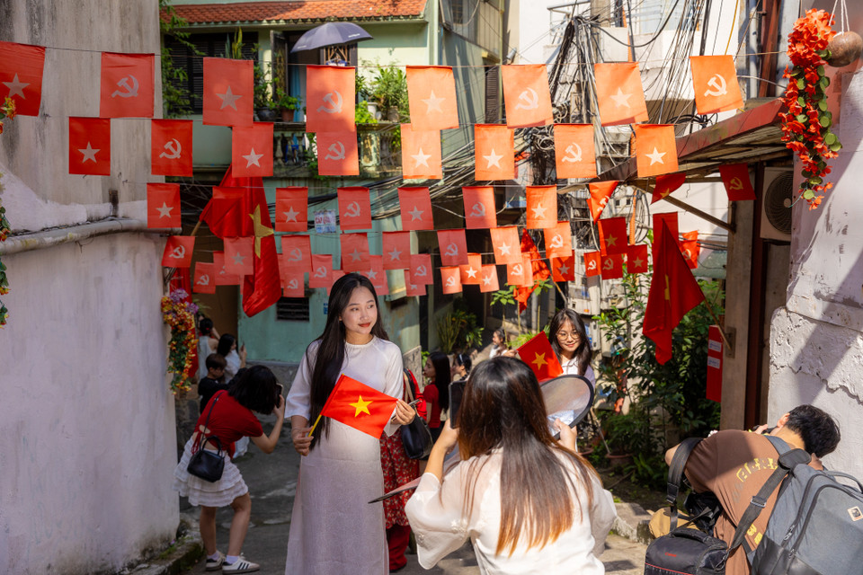 Một con ngõ nhỏ trên phố Yên Phụ những ngày này đều tấp nập các bạn trẻ đến chụp ảnh. Có lá cờ được treo từ lâu đã bạc màu theo thời gian nhưng vẫn giữ nguyên ý nghĩa sâu sắc. (Ảnh: Minh Sơn/Vietnam+)