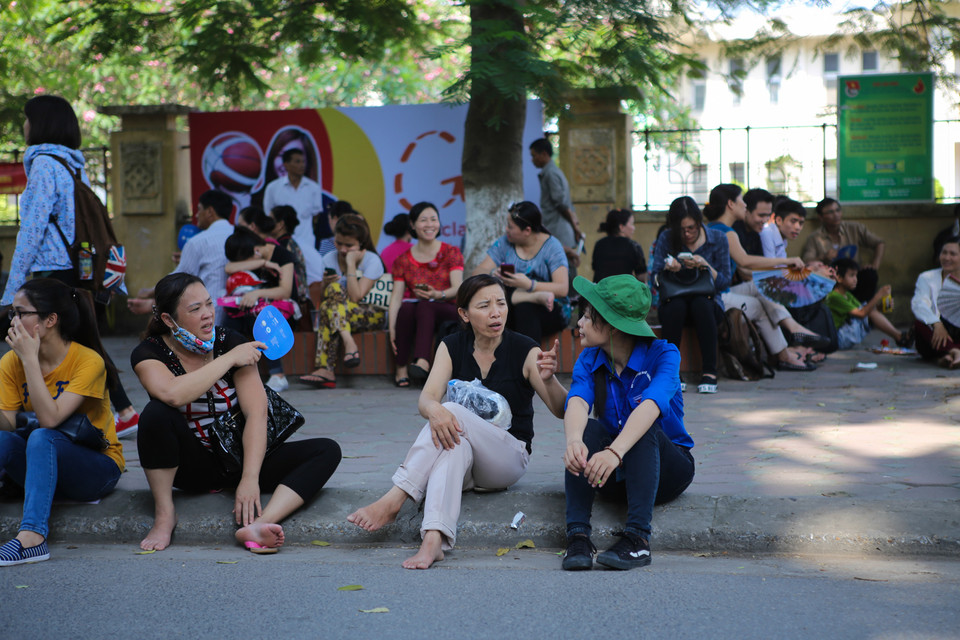 Một phụ huynh chia sẻ, cô không an tâm nên đã cố gắng đứng chờ con trước điểm thi Đại học quốc gia trong thời tiết oi bức. (Ảnh: Minh Sơn/Vietnam+)