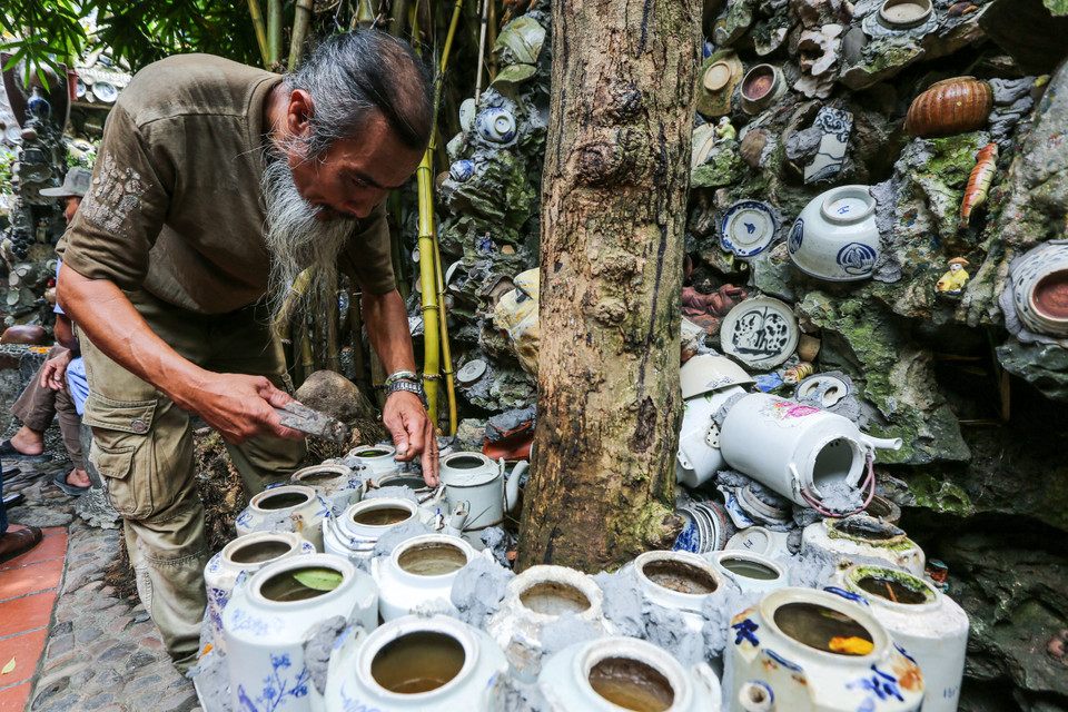 Ban ngày rảnh rỗi ông lại đi sưu tầm đồ cổ. Đêm đến ông lại hì hục trộn ximăng và cát để gắn bát đĩa lên tường. Vất vả là thế nhưng ông không thấy mệt. Bởi chính ông cũng không hiểu vì sao mấy cái 'bát đĩa cũ' lại hấp dẫn ông đến vậy. (Ảnh: Minh Sơn/Vietnam+)