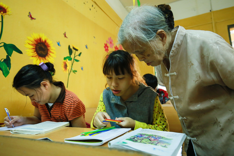 Khi thì bà kiểm tra tính toán của một em nhỏ. (Ảnh: Minh Sơn/Vietnam+)