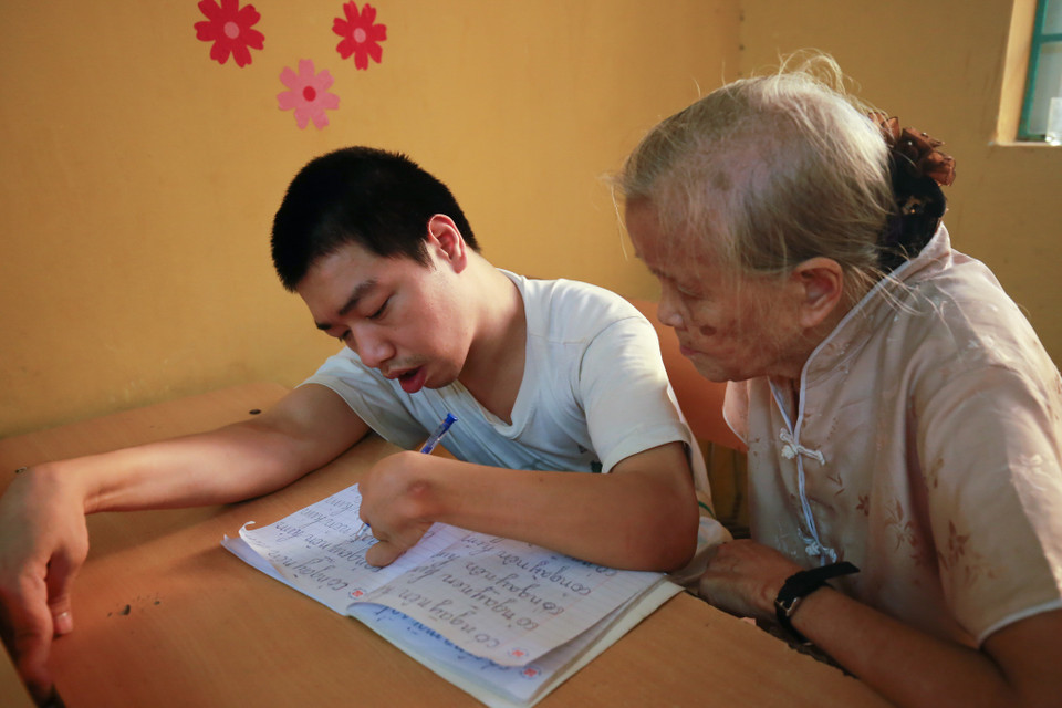 Khác với học sinh thường, những em học sinh khuyết tật được bà tận tình cầm tay, chỉ dẫn, uốn nắn từng chữ O, chữ A. (Ảnh: Minh Sơn/Vietnam+)