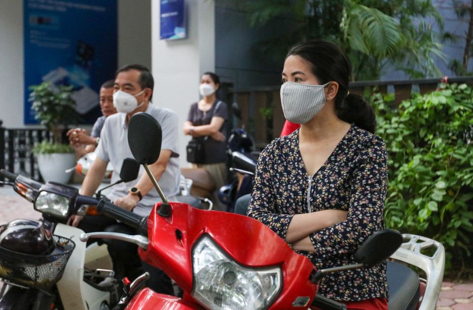 Chị Quý (quận Long Biên, Hà Nội) sốt ruột ngồi chờ con phía ngoài cổng trường. 'Mặc dù cháu cũng nói với mẹ rằng con tự tin nhưng tôi vẫn lo lắng như ngồi trên đống lửa,' chị Quý nói. (Ảnh: Minh Hiếu/Vietnam+)