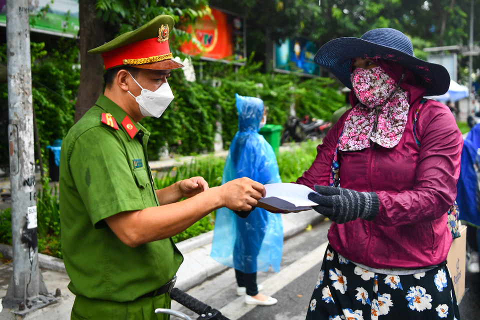 Lực lượng chức năng liên tục kiểm tra từng trường hợp đi qua chốt kiểm soát. Người dân đều chấp hành việc kiểm tra giấy đi đường. (Ảnh: Minh Sơn/Vietnam+)