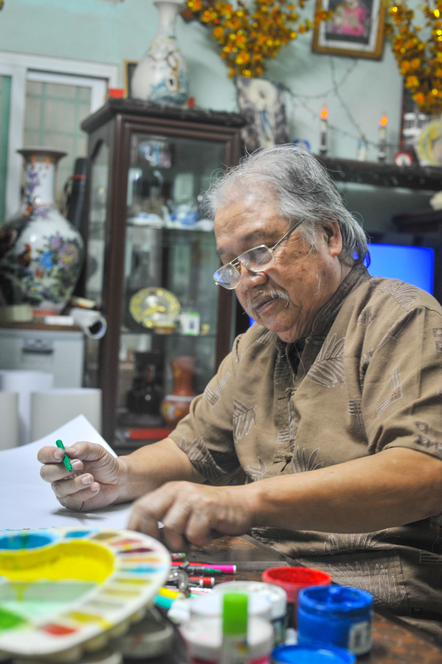 Việc vẽ báo tường với ông phải nói đến chữ ‘duyên’. Khi còn tại ngũ năm 1968, ông đã thường xuyên vẽ ký họa cuộc sống thường ngày của đồng đội, lúc chiến đấu, khi là cảnh sinh hoạt văn nghệ. (Ảnh: Minh Sơn/Vietnam+)