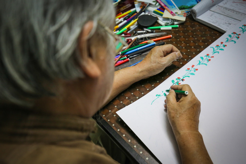 Ngoài sự sáng tạo và cẩn thận trong từng nét vẽ, điều quan trọng với ông là hiểu được ý của khách hàng, phải làm được nhiều hơn những gì họ muốn truyền tải trong tờ báo tường. (Ảnh: Minh Sơn/Vietnam+)