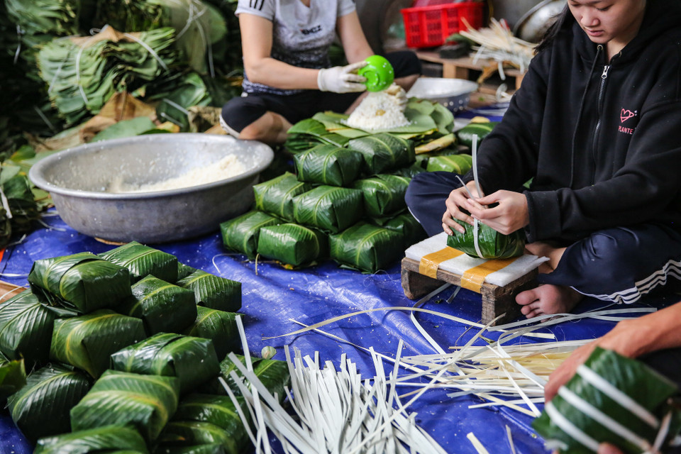 Mỗi người phụ trách một công đoạn từ rửa lá, vo gạo, đãi đỗ, ướp thịt làm nhân… tất cả đều tập trung vào công việc của mình. (Ảnh: Minh Sơn/Vietnam+)