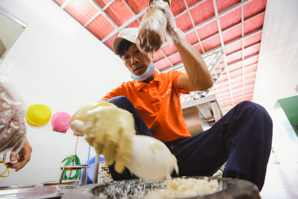 Giã tay là công đoạn vất vả nhất, thoạt nhìn những người thợ thạo việc vung chày lên xuống một cách nhẹ nhàng, nhưng những con mực khi được giã bắt đầu sệt lại, kết dính thành một hỗn hợp dẻo đặc như keo làm cho việc vung chày trở nên khá vất vả, chỉ những thợ quen tay mới có thể đảm đương công đoạn này. (Ảnh: Minh Sơn/Vietnam+)