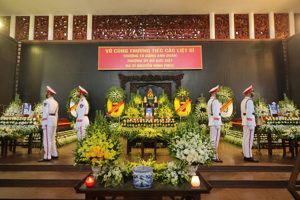 Xung quanh ban thờ chung là các vòng hoa vàng, trắng đan xen. Tiếp đó, 3 linh cữu của các liệt sĩ được quàn trang trọng chính giữa, hoa hồng bao phủ dưới chân. Phía trước là bát hương, di ảnh từng đồng chí cùng đài hoa thơm ngát, với các huân, huy chương, phần thưởng cao quý. (Ảnh: Hoài Nam/Vietnam+)