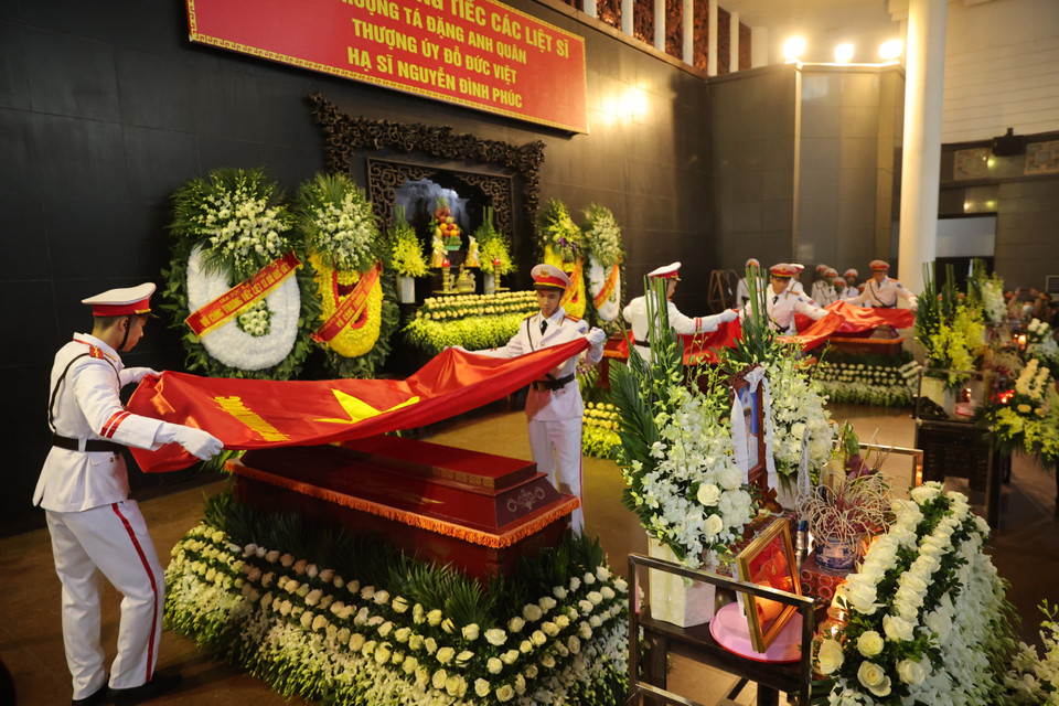 Ban Tổ chức lễ tang thực hiện nghi lễ phủ cờ Tổ quốc lên linh cữu của 3 Liệt sỹ. (Ảnh: Hoài Nam/Vietnam+)