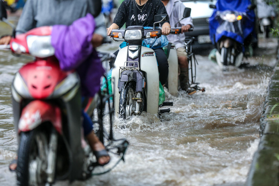 Nhiều phương tiện bất chấp nguy hiểm vẫn phóng xe qua khu vực ngập. (Ảnh: Minh Sơn/Vietnam+)