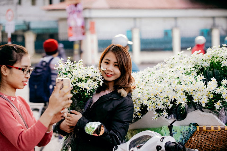 Nhiều bạn trẻ không những mua hoa mà còn lựa chọn đây là một trong những địa điểm chụp ảnh không thể thiếu. (Ảnh: PV/Vietnam+)