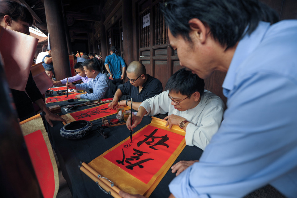 Viết không xuể trong khi hàng trăm người đứng đợi xung quanh. (Ảnh: Minh Sơn/Vietnam+)