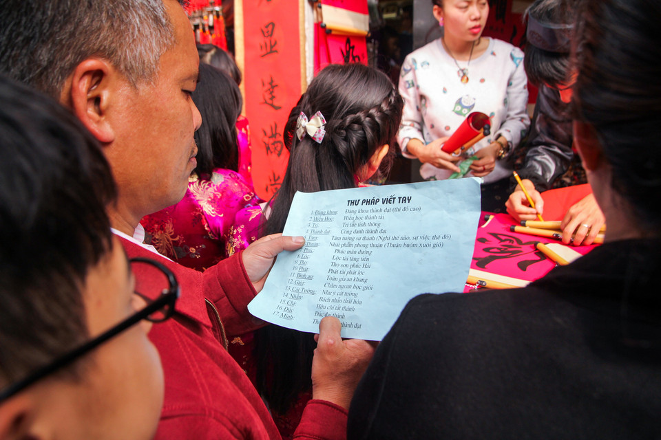 Có người không thuộc nhiều mặt chữ nên phải đọc bảng chú giải để xin đúng chữ theo ý muốn. (Ảnh: Minh Sơn/Vietnam+)