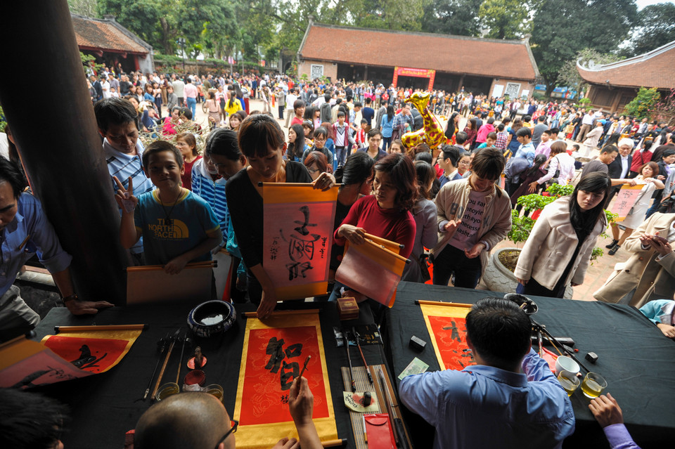 Nhưng khi vào đến tận nơi xin chữ, tình trạng lộn xộn lại diễn ra, nhiều người khá vất vả để nhờ được ông đồ viết được chữ. (Ảnh: Minh Sơn/Vietnam+)