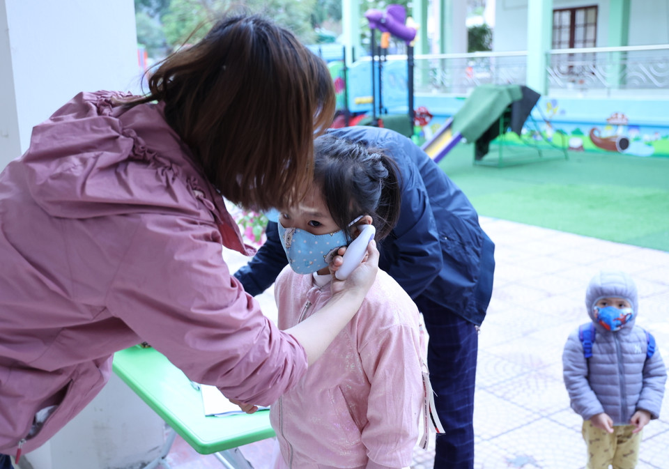 ...trong khi các con được cô giáo đo thân nhiệt và hướng dẫn rửa tay trước khi vào lớp. (Ảnh: Tá Hiển/Vietnam+)