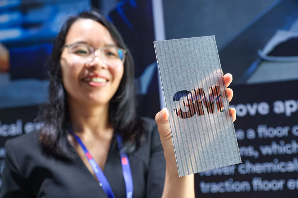 Hướng dẫn viên giới thiệu những vật liệu phim dán giả kim loại, gỗ,... để trang trí nội thất của 3M. (Ảnh: Minh Sơn/Vietnam+)