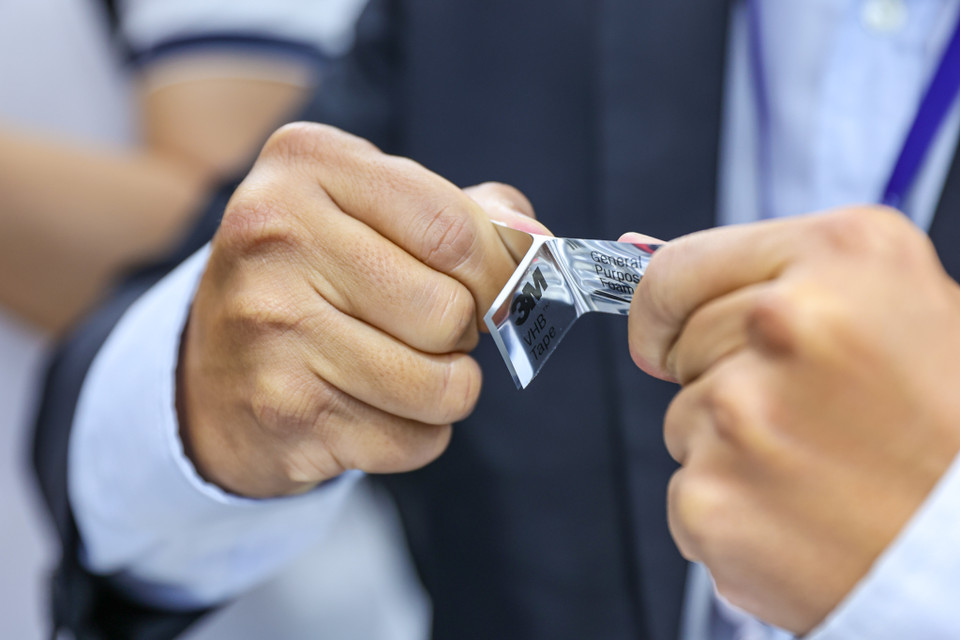 Một khách hàng được thử nghiệm độ chắc chắn của băng dính 3M. (Ảnh: Minh Sơn/Vietnam+)