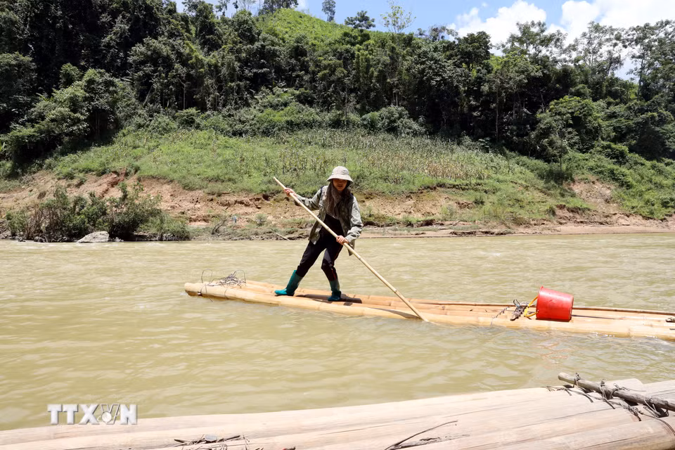 Người Dao ở xóm Song Phụ, thôn Khuổi Luông, xã Quý Hòa (Lạng Sơn) vượt qua sông Bắc Giang bằng bè mảng ghép tạm từ những cây luồng. (Ảnh: Văn Đạt/TTXVN)