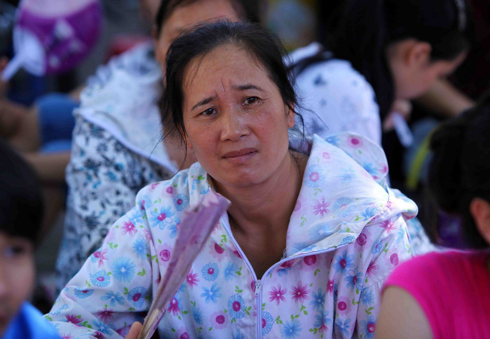 Tâm trạng lo lắng giữa cái nóng khiến sự chờ đợi của các bậc phụ huynh trong lúc con thi khiến thời gian như dài thêm. (Ảnh: Quý Trung/TTXVN)