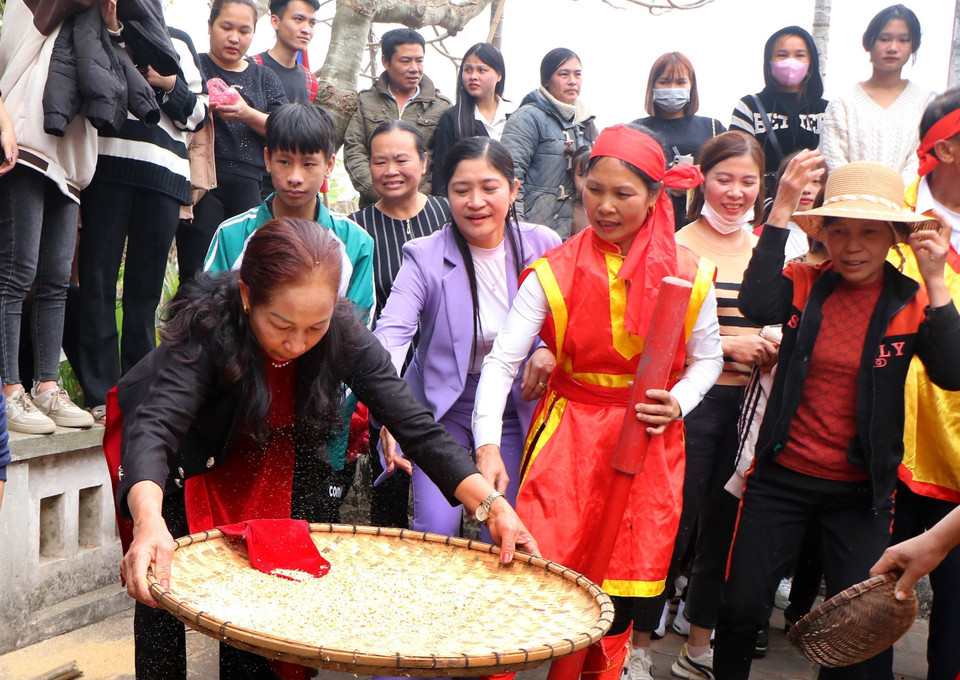 Trong lúc đàn ông kéo lửa thì chị em phụ nữ thay nhau giã thóc, sàng, sảy cho ra có những hạt gạo trắng để phục vụ cho cuộc thi. Ảnh: Trung Kiên - TTXVN