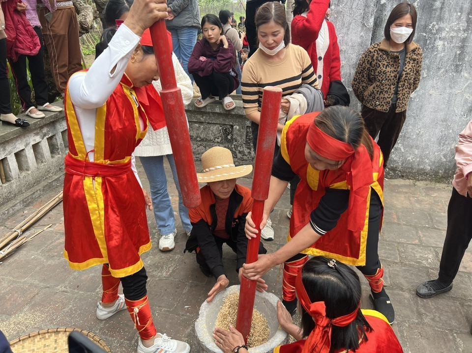 Trong khi đàn ông kéo lửa, thì phụ nữ cũng tất bật thi nhau giã gạo. (Ảnh: Trung Kiên/TTXVN)