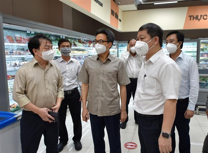 Phó Thủ tướng Vũ Đức Đam nghe báo cáo công tác chuẩn bị hàng hóa cho người dân trong thời gian giãn cách xã hội tại siêu thị Coop Mart đường Trường Chinh, quận Tân Bình, (Thành phố Hồ Chí Minh). (Ảnh TTXVN)