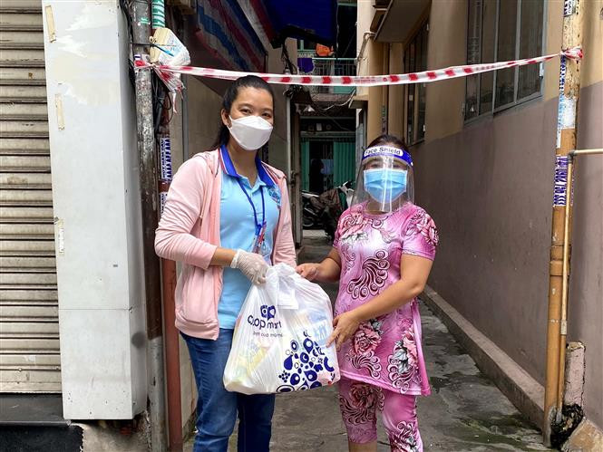Tình nguyện viên giao hàng hóa mua giúp người dân Thành phố Hồ Chí Minh trong những ngày thực hiện giãn cách xã hội. (Ảnh: Thanh Vũ/TTXVN)