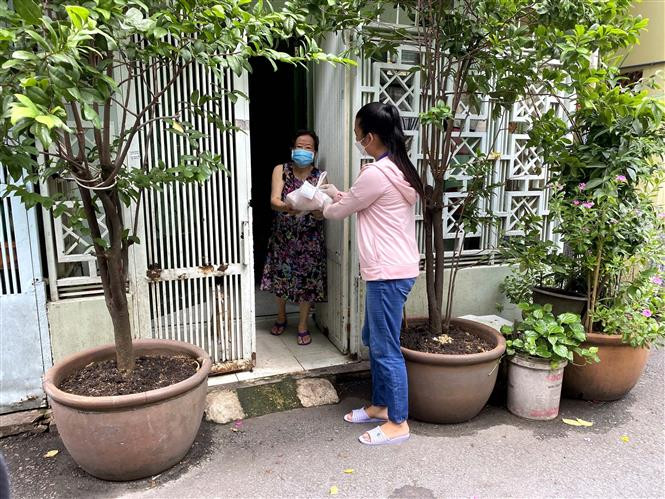 Tình nguyện viên bàn giao hàng hóa mua giúp người dân trong những ngày thực hiện giãn cách xã hội. (Ảnh: Thanh Vũ/TTXVN)