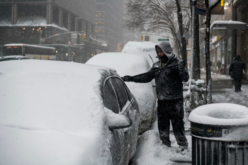 Cạo tuyết đóng dày trên nóc xe ôtô ở New York, ngày 4/1. (Nguồn: AFP)