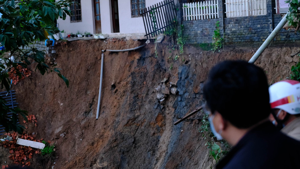 Đoạn sạt lở chạy dài phía sau nhà dân khoảng 50m, tạo thành một lòng chảo, chôn vùi rất nhiều đồ đạc. (Ảnh: Ngọc Dũng/TTXVN)