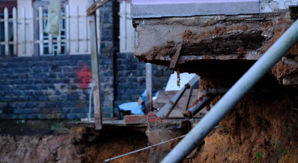 Đoạn sạt lở chạy dài phía sau nhà dân khoảng 50m, tạo thành một lòng chảo, đe dọa đến sự an toàn của nhiều ngôi nhà. (Ảnh: Ngọc Dũng/TTXVN)