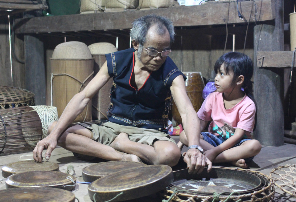 Nghệ nhân Đinh Bi bên bộ cồng chiêng quý mà ông gìn giữ hàng chục năm nay. (Ảnh: Hồng Điệp/TTXVN)